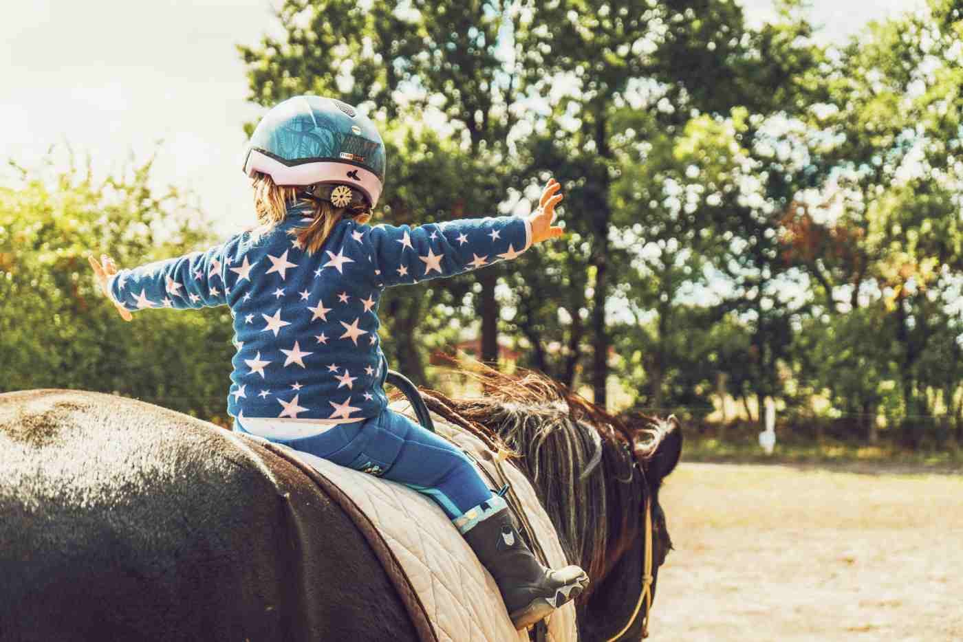 criança no cavalo em aula de equitação